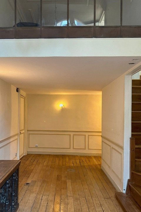 Avant : pièce vide sous mezzanine, parquet ancien usé et soubassement mouluré défraîchi