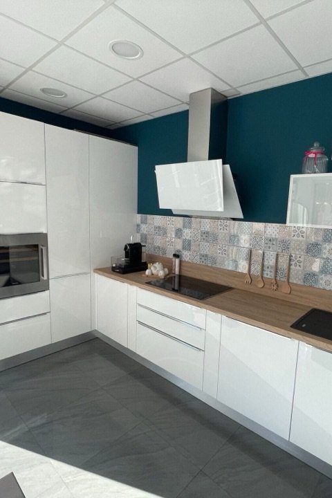 Cuisine blanche laquée avec mur bleu canard et crédence en carreaux de ciment