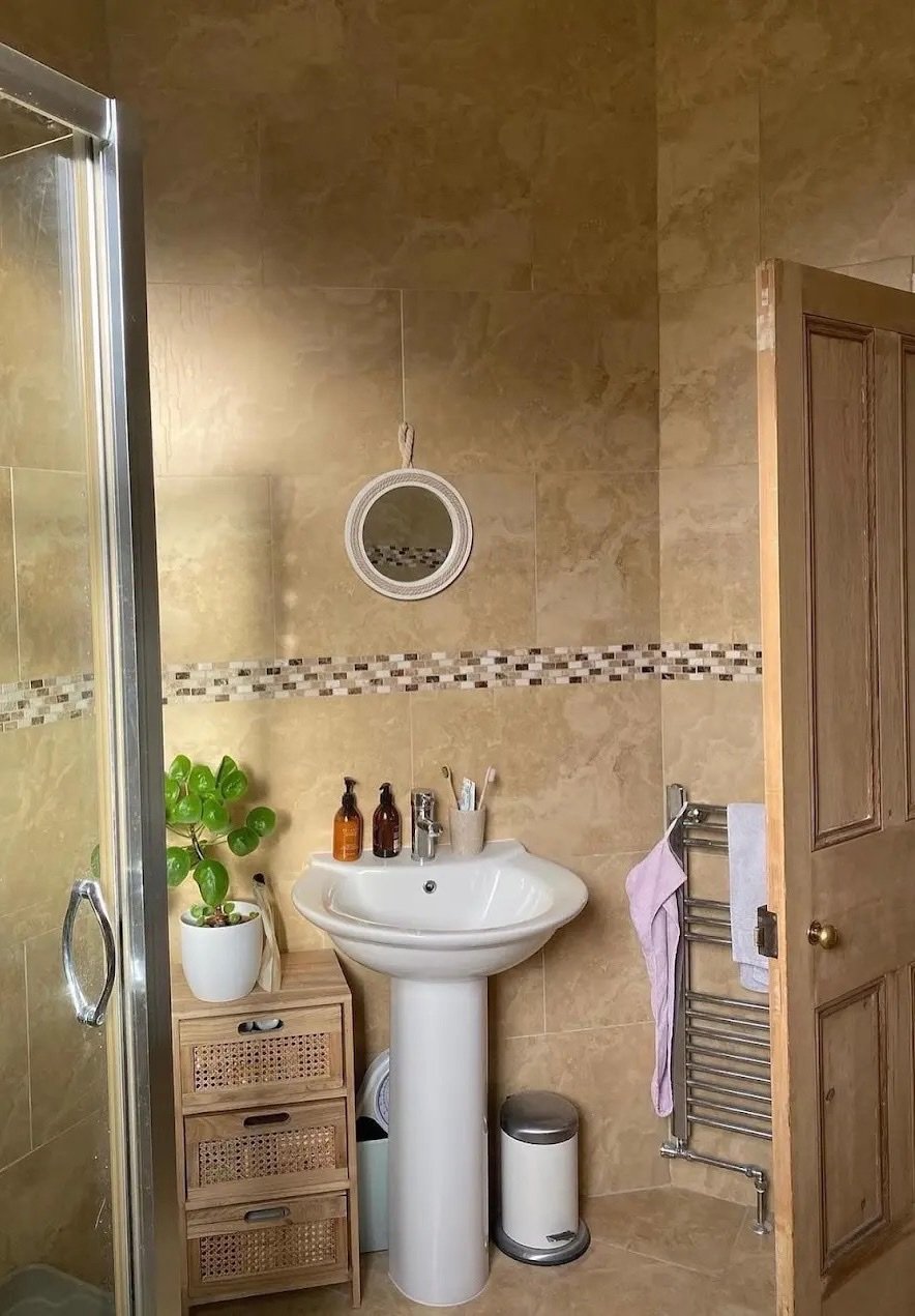 Avant : salle de bains entièrement carrelée en travertin beige, vasque sur colonne, frise en mosaïque et sèche-serviettes chromé